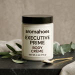 Aromahoes Executive Prime Body Crème jar on a black marble surface with eucalyptus leaves and a gold spoon.